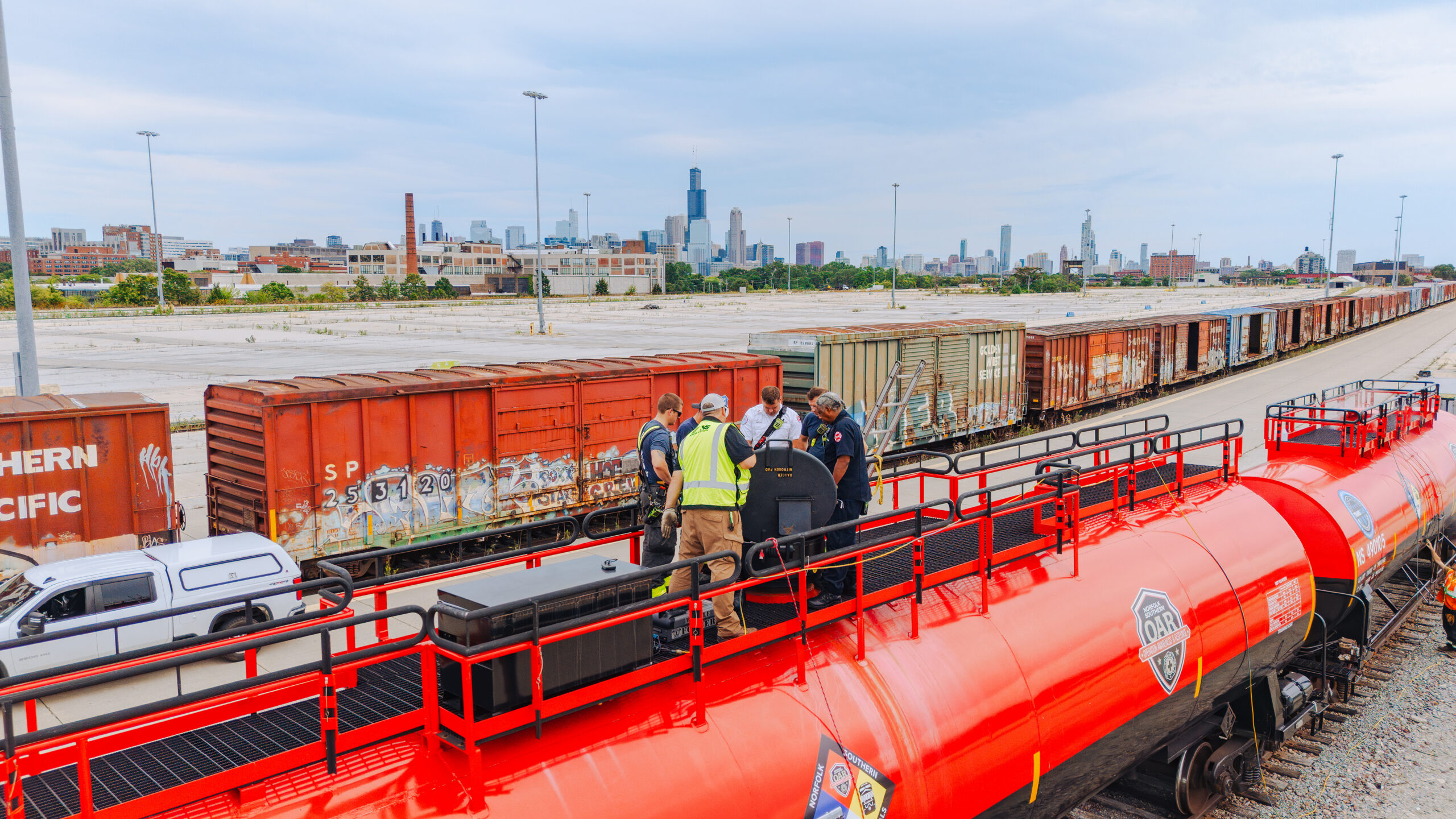 First responders training beside Norfolk Southern rail equipment with the Chicago skyline in the background