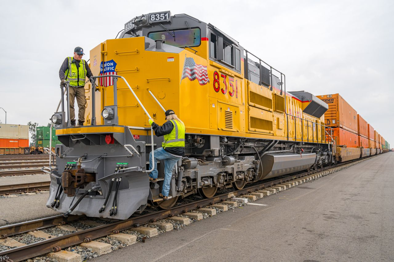 Union Pacific crew members on locomotive 8351 alongside an intermodal train