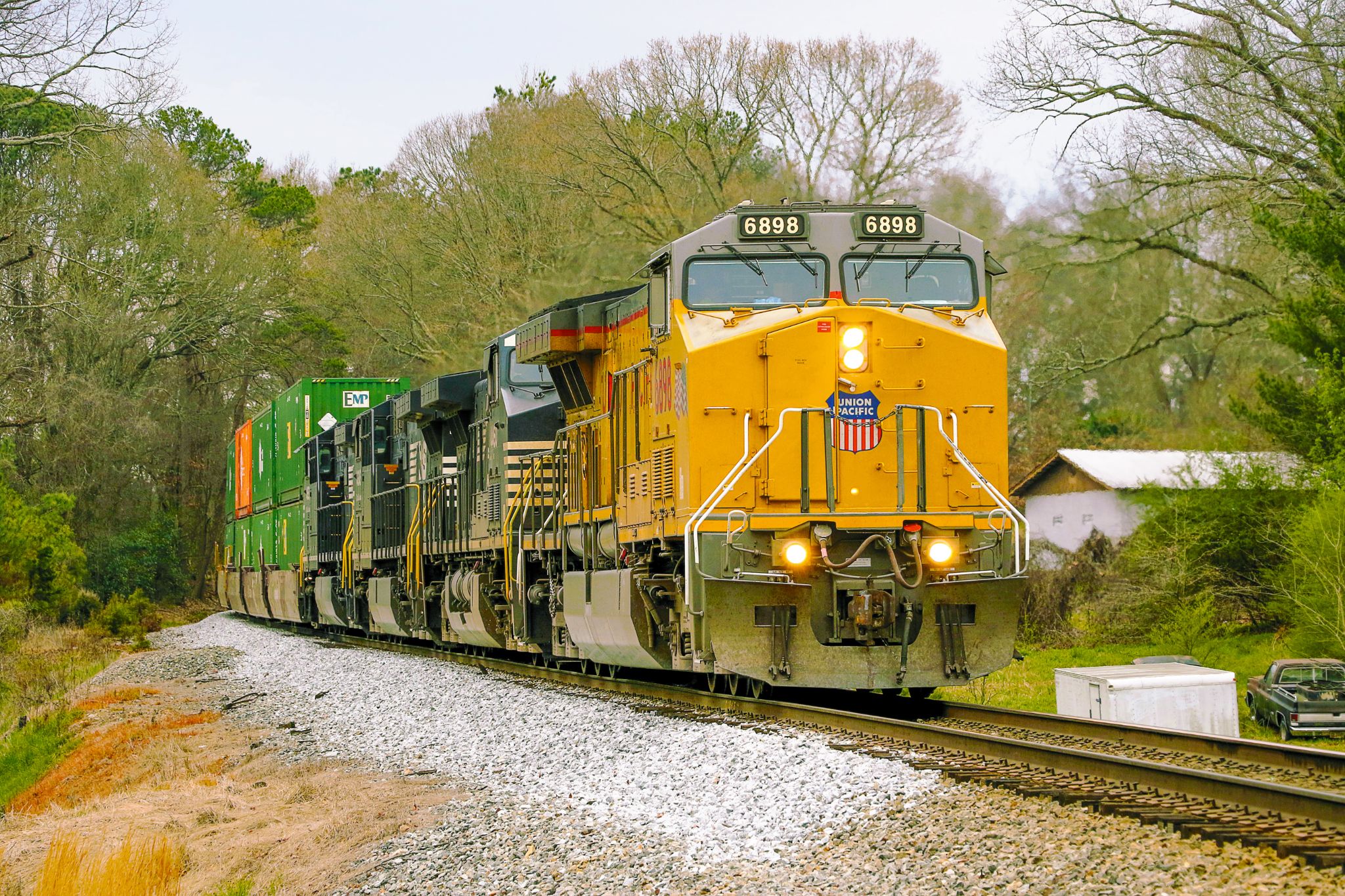 Union Pacific locomotive 6898 leading an intermodal freight train through a wooded landscape.